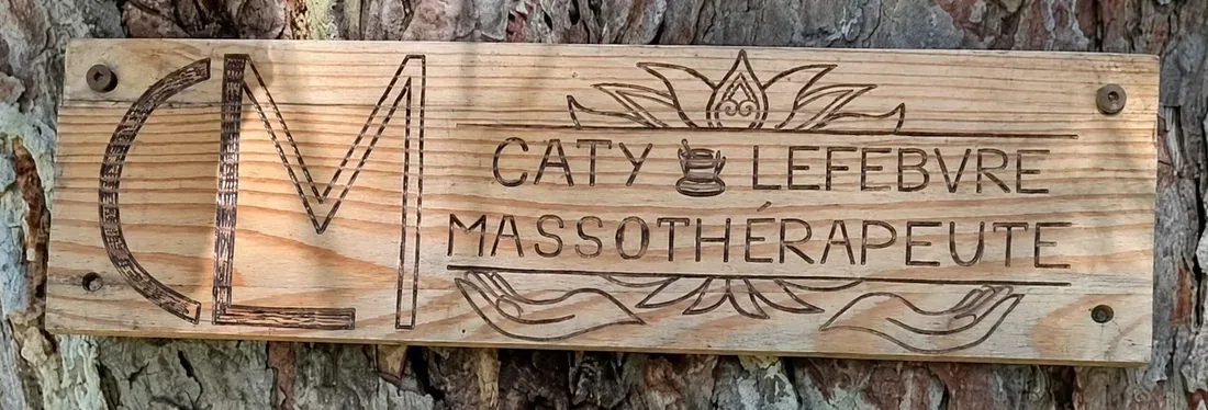 Pancarte en bois de Caty Lefebvre, massothérapeute, fixée à un arbre à l’entrée du terrain